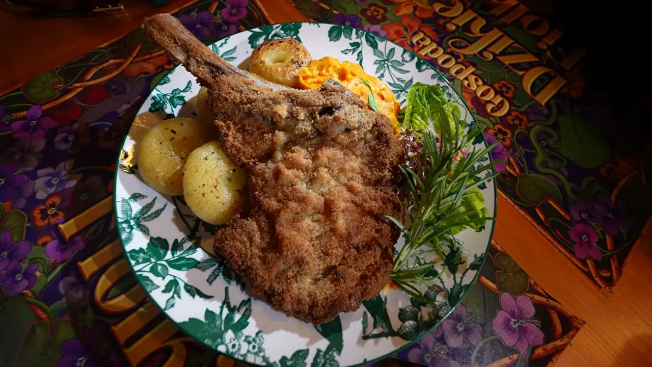 Panierowany kotlet cielęcy z kością, kluski śląskie i pure marchewkowe na talerzu w Gospodzie Dzikie Fiołki